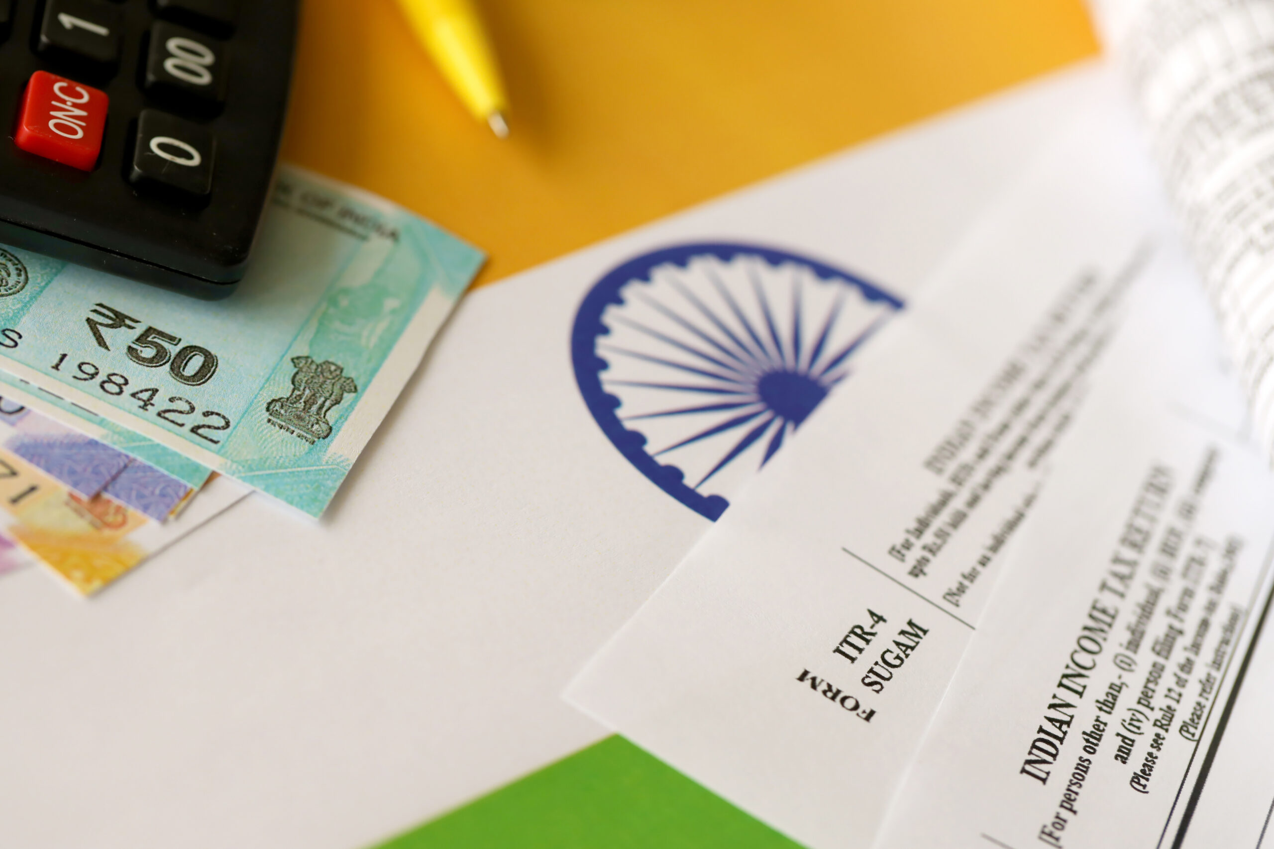 Indian income tax return blank form with pen and indian rupees bills on indian country flag close up. Annual tax report concept