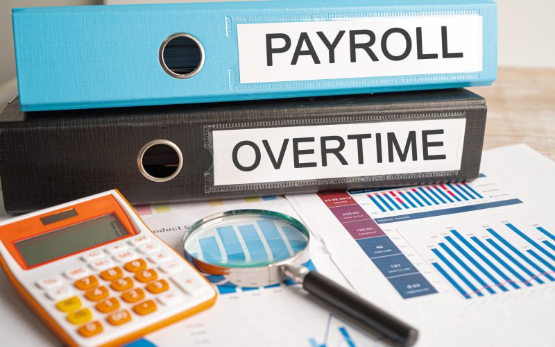 Payroll and Overtime. Binder data finance report business with graph analysis in office.